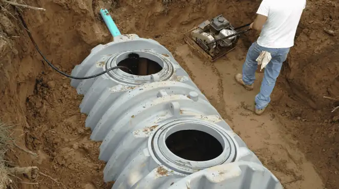 Septic tank installation showing a technician compacting soil around a new poly septic tank in an excavation pit in Bradenton, FL